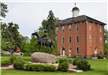An outside view of town hall with a statue of a man on a horse and grounds